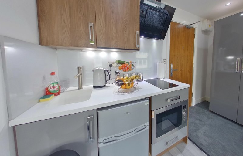 Modern kitchen with white countertop, wooden cabinets, stainless steel appliances and kettle
