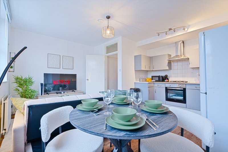Open-plan kitchen and dining area with round table, place settings, and modern appliances