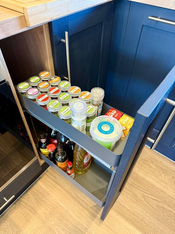 Kitchen drawer open showing jars, glasses, plates and branded food items