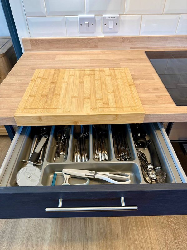 Kitchen counter with open drawer displaying utensils and cutlery organizers