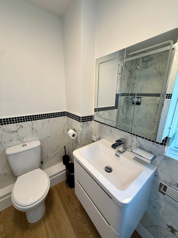 Modern bathroom with white vanity, sink, toilet, shower cubicle and black tile border