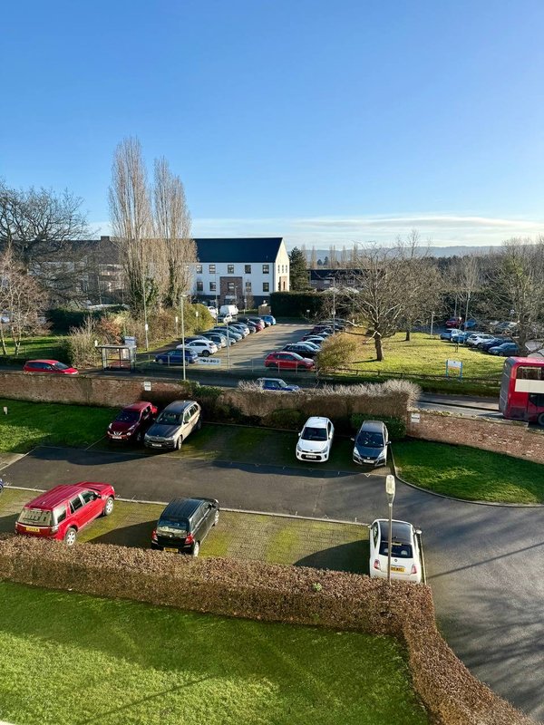 Aerial view of property exterior with parking area, surrounding grounds and landscape