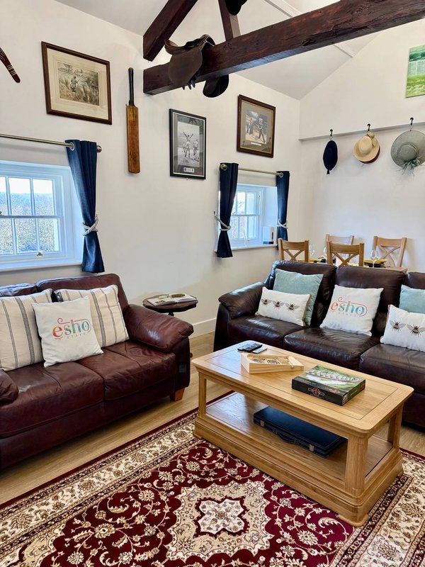 Living room with dark leather sofas, wooden coffee table, exposed beams and framed wall art