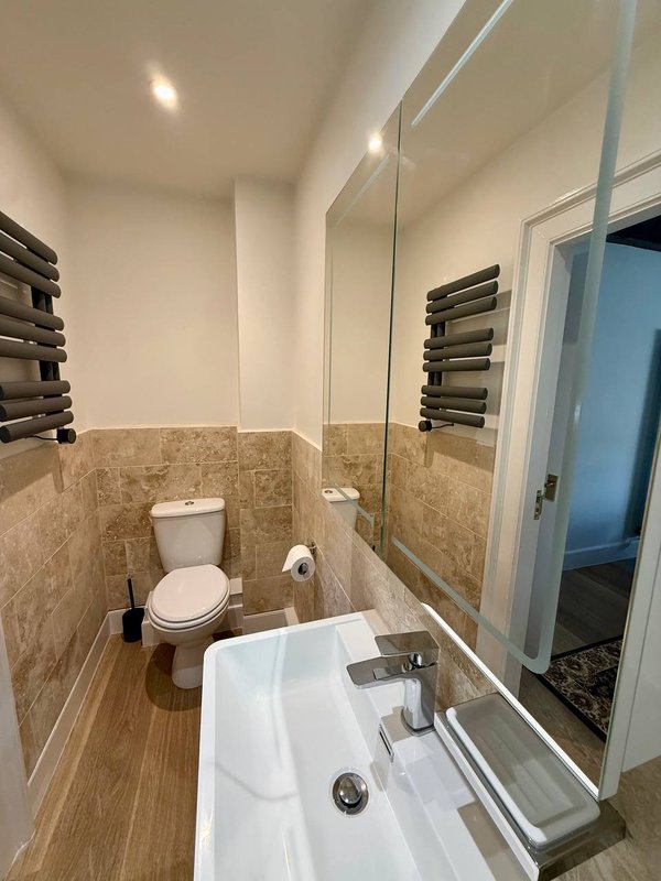 Modern bathroom with toilet, white sink, mirror and heated towel rail