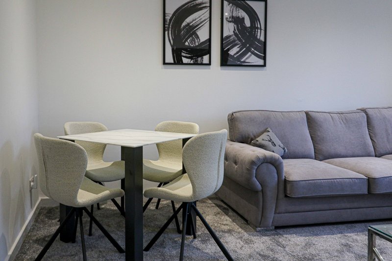 Modern living room with dining table, upholstered chairs, grey sofa and wall art