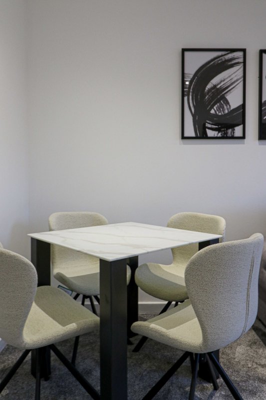 Modern meeting room with white table, four upholstered chairs and abstract wall art