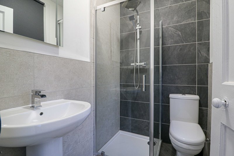 Modern bathroom with pedestal sink, enclosed shower cubicle, toilet and mirror