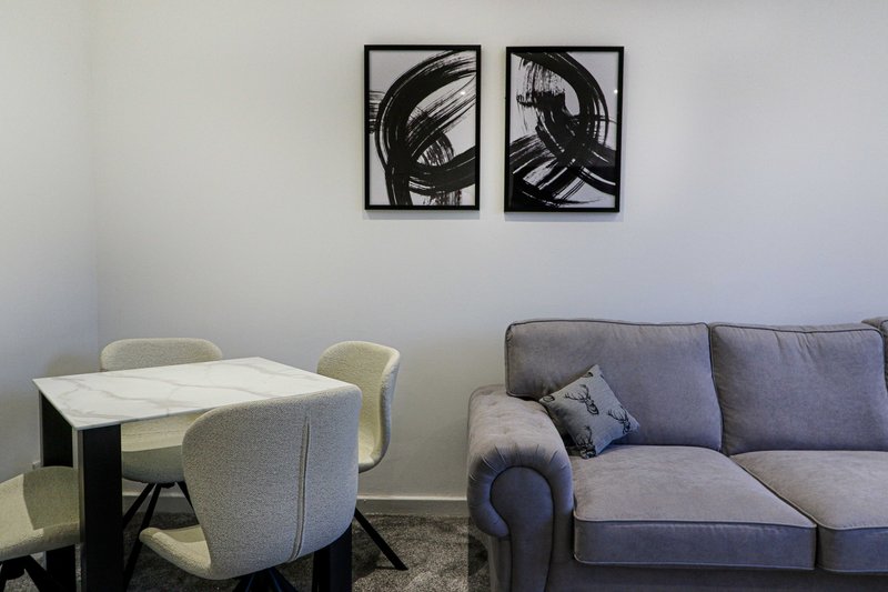 Modern living room with dining table, upholstered chairs, gray sofa and abstract wall art