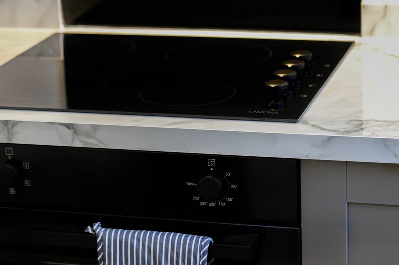 Modern kitchen with black induction cooktop, marble countertop and built-in oven
