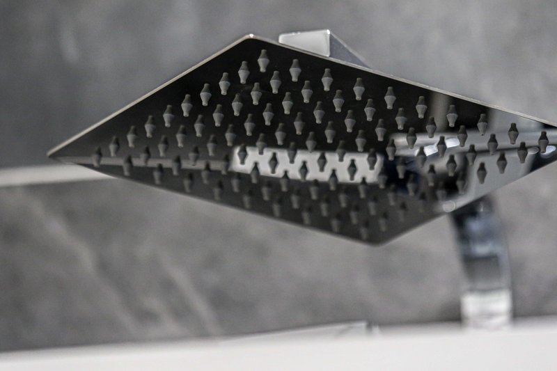 Close-up of modern black square rainfall showerhead mounted on ceiling
