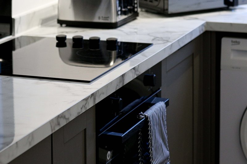 Modern kitchen with white marble countertop, black cabinetry, and integrated appliances