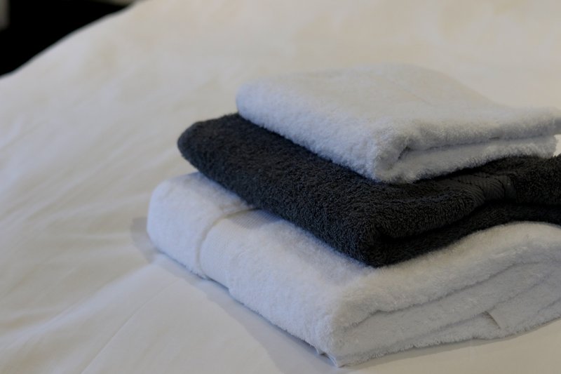 Stack of folded towels in white and black on white bedding