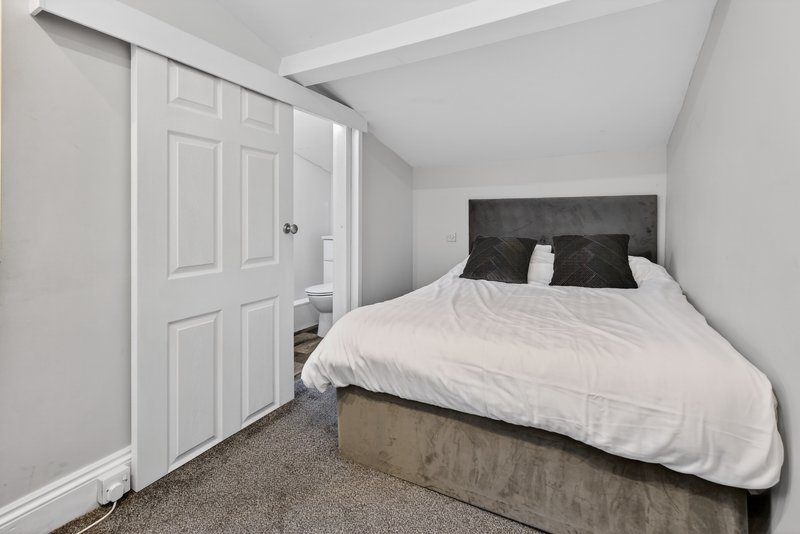 Bedroom with double bed, dark headboard, white bedding, wardrobe and carpeted floor