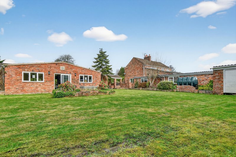 Brick residential property with large garden, green lawn and detached outbuildings