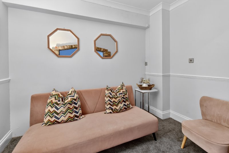 Modern living room with tan sofa, geometric patterned cushions, wooden mirrors and side table