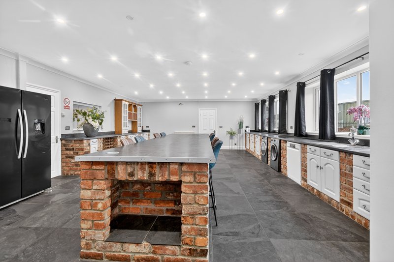 Modern open-plan kitchen with brick island, stainless steel appliances and large windows