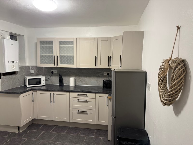 Modern kitchen with cream cabinetry, dark worktops, stainless steel appliances and rope decoration