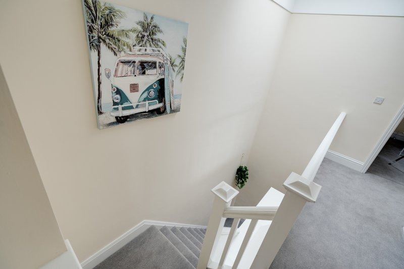 Stairwell with white railings, cream walls, and decorative wall art of vintage van