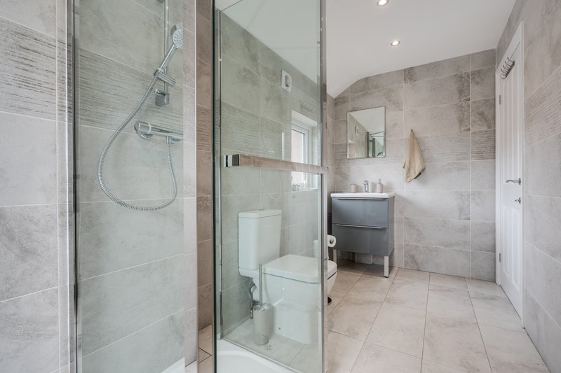 Modern bathroom with walk-in shower, toilet, sink vanity and tiled flooring