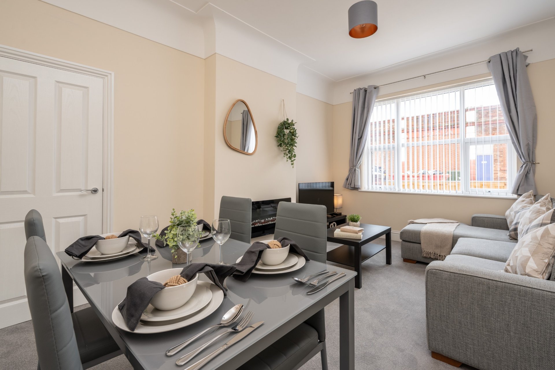 Open-plan living and dining area with grey dining table, sofa, and kitchen area visible