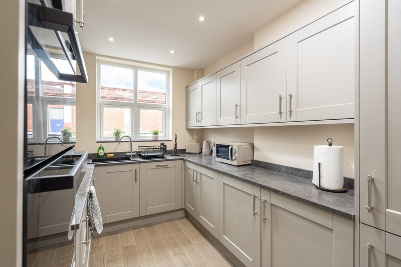 Modern kitchen with cream cabinetry, black worktops, stainless steel appliances and wooden flooring