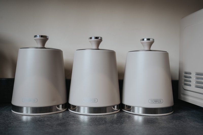 Three cream kettle appliances with stainless steel bases on kitchen counter