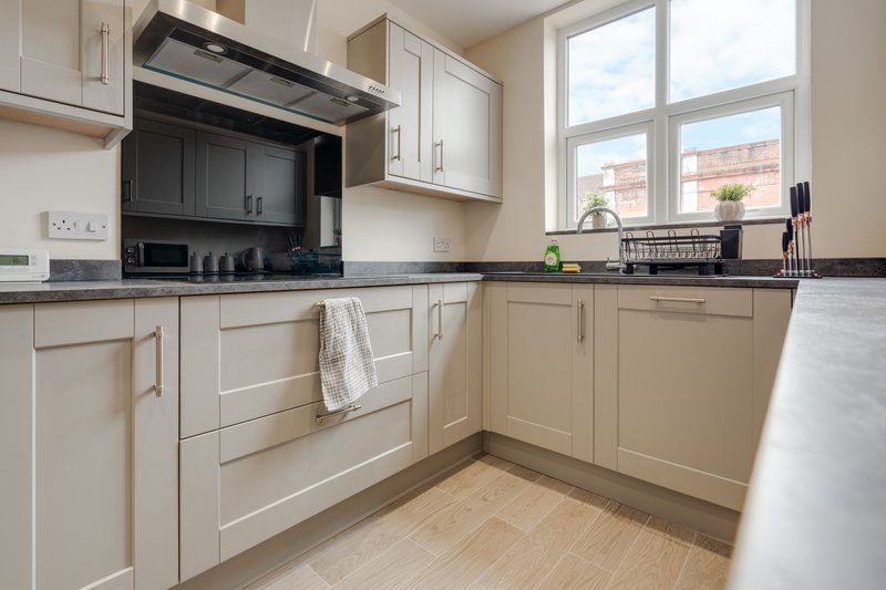 Modern kitchen with cream cabinets, black countertop, stainless steel appliances and bright window