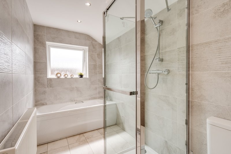 Modern bathroom with walk-in shower, bathtub, window and neutral tile finishes