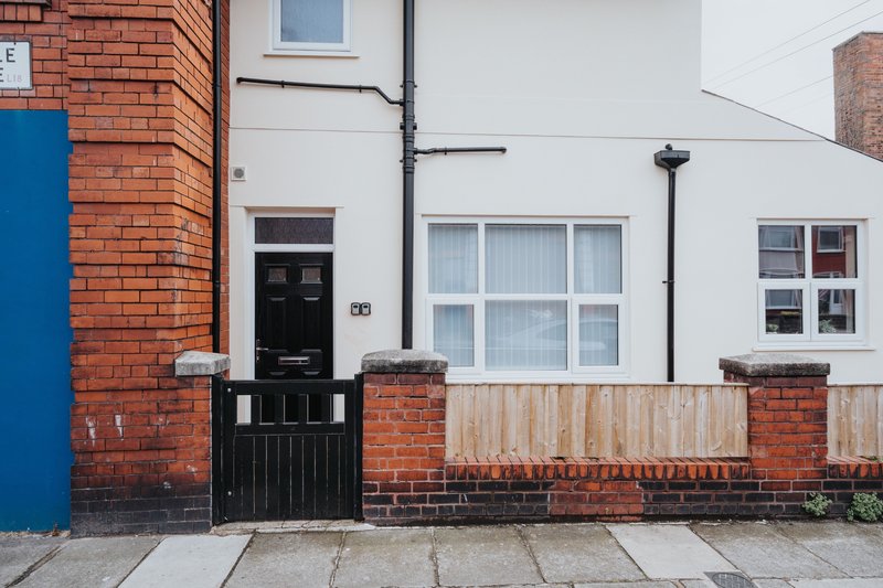 Brick terraced house exterior with black front door, white-framed windows and brick wall detailing