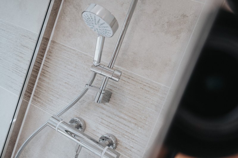 Bathroom shower wall with overhead rainfall showerhead, handheld spray, and chrome fixtures