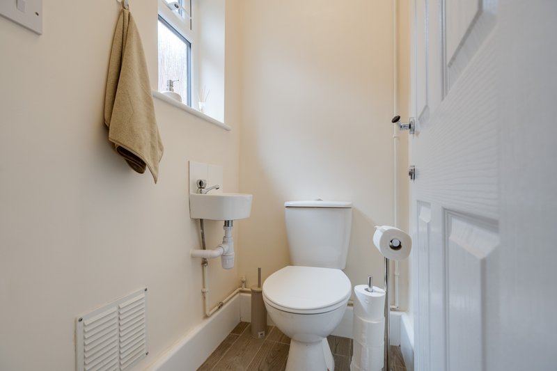 Small bathroom with toilet, pedestal sink, towel rail and small window