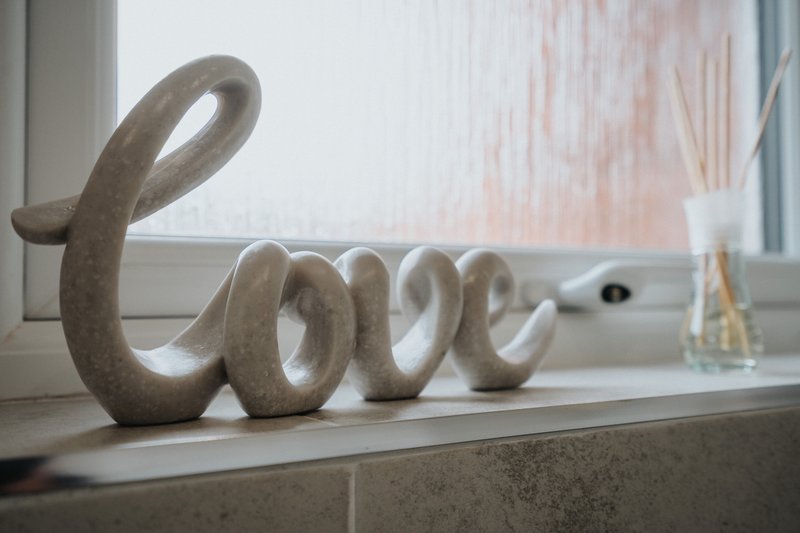 Windowsill with decorative stone 'love' sculpture and glass vase