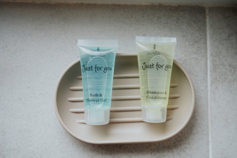 Two toiletry bottles on a ceramic tray, typical bathroom amenities display