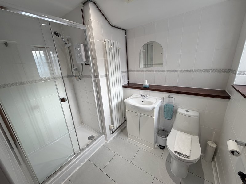 Clean modern bathroom with shower enclosure, vanity sink, toilet and circular mirror