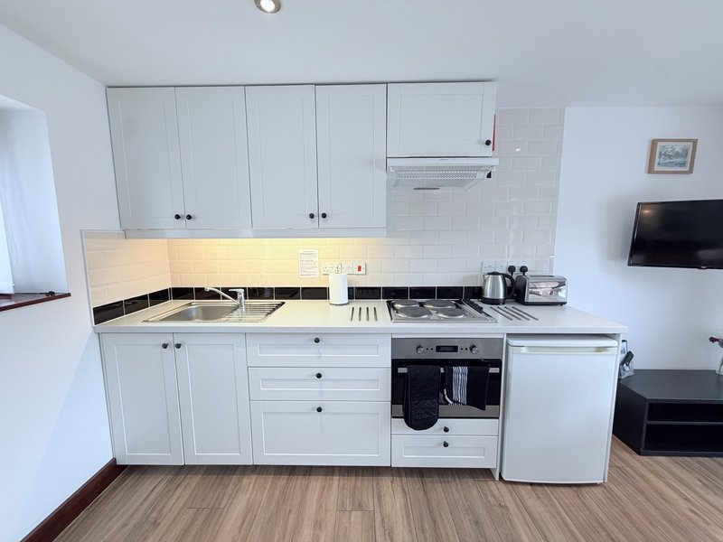 Modern white kitchen with fitted cabinets, gas hob, oven and integrated appliances