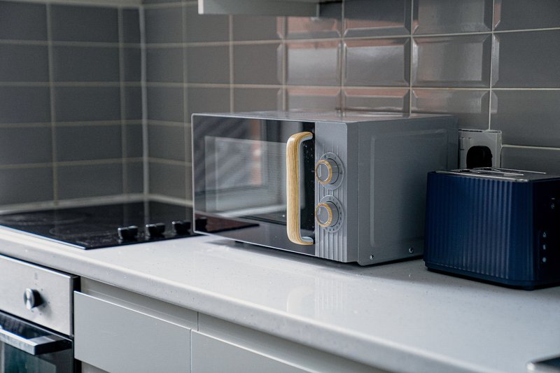 Modern kitchen counter with microwave, toaster, and cooktop behind tiled backsplash