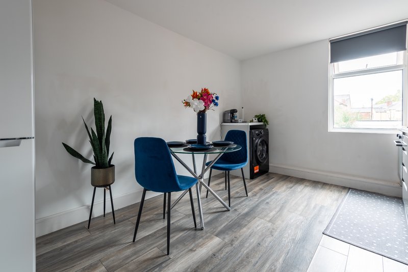 Modern kitchen-dining area with blue chair, small table, potted plant and window