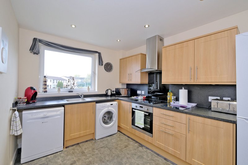 Modern kitchen with wooden cabinets, black countertops, integrated appliances and window