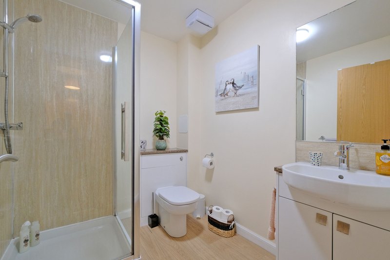 Modern bathroom with walk-in shower, toilet, double sink vanity and wooden flooring