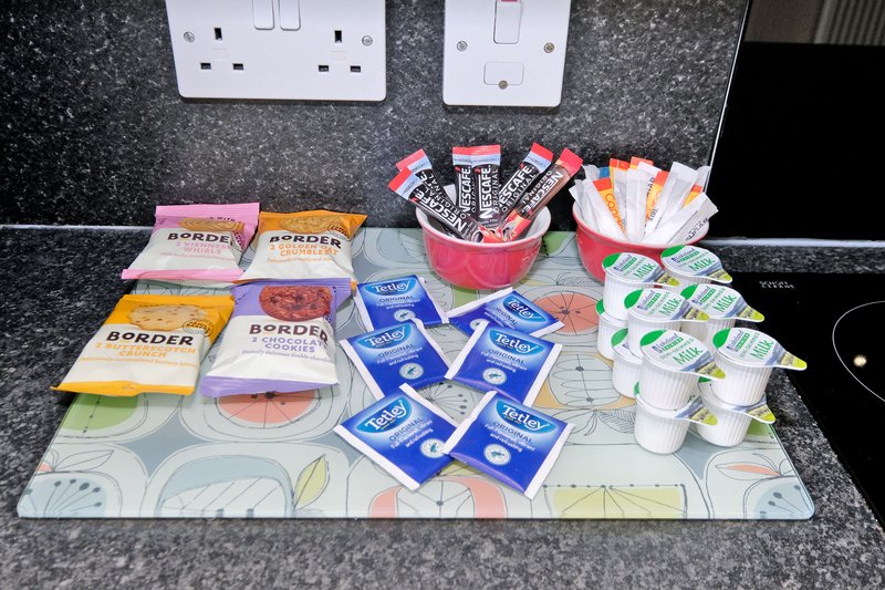 Kitchen counter with arranged condiments, snacks, and toiletries near white outlets