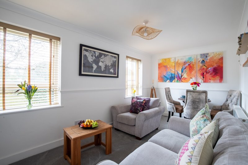 Bright living room with grey sofas, wooden coffee table, framed world map and colorful abstract artwork