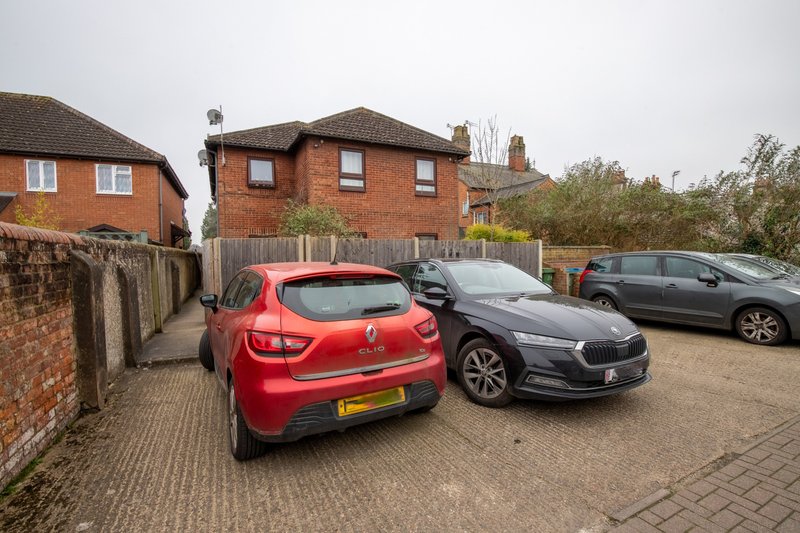 Red brick detached house with driveway, three parked cars and brick boundary wall