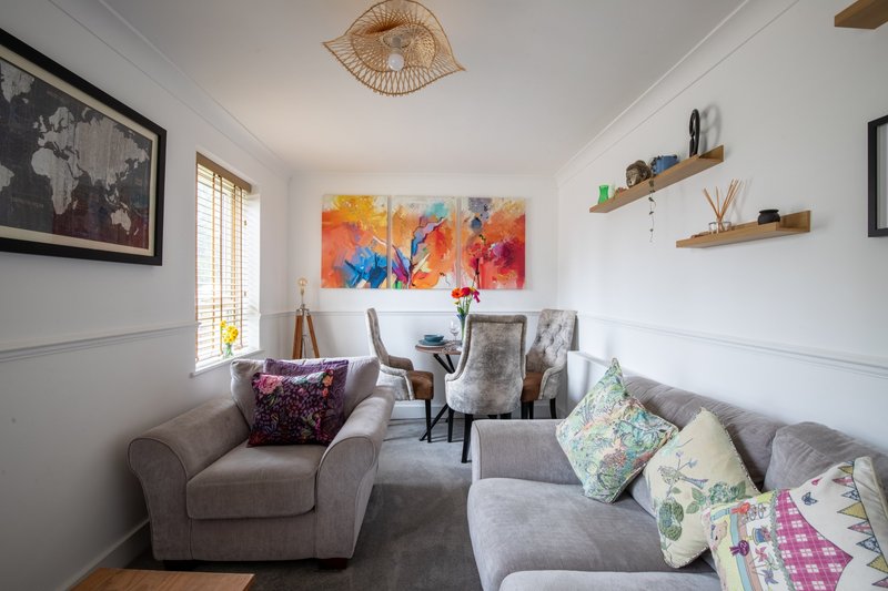 Bright living room with grey sofa, colorful abstract wall art, and decorative cushions