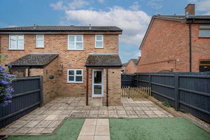 Brick terraced house exterior with paved patio, small garden, and black fencing
