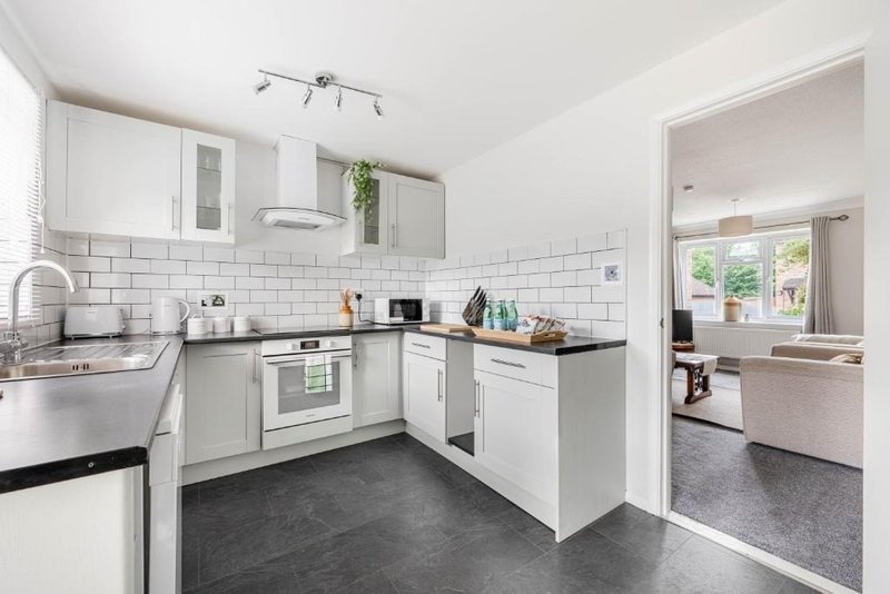 Modern white kitchen with black worktops, subway tile backsplash and stainless steel appliances