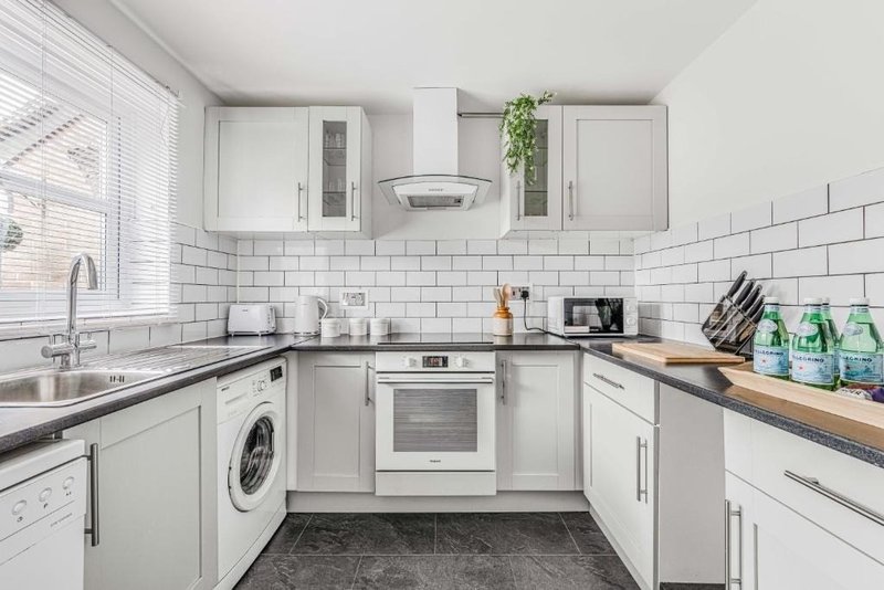 Modern white kitchen with subway tile backsplash, stainless steel appliances and wooden countertops