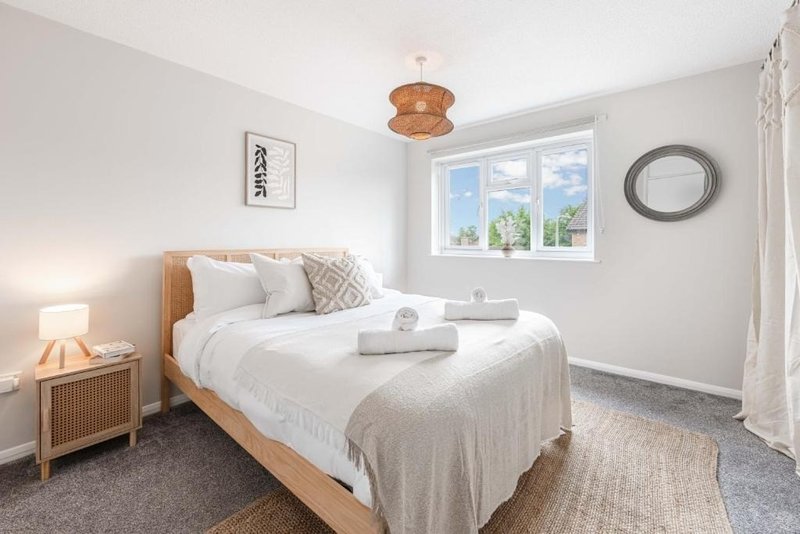 Bright bedroom with wooden bed, white bedding, wooden nightstand and warm lighting