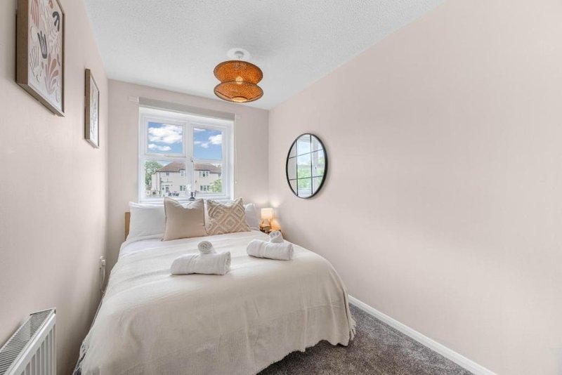 Small bedroom with single bed, window view, amber ceiling light and wall mirror