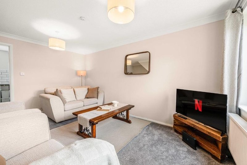 Modern living room with cream sofa, wooden coffee table, TV, and pink accent walls