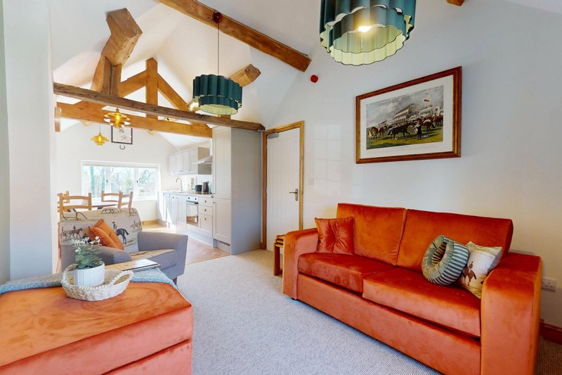 Exposed beams, warm furnishings and countryside-inspired décor give the room a welcoming and characterful feel, with the kitchen and dining area conveniently adjoining.